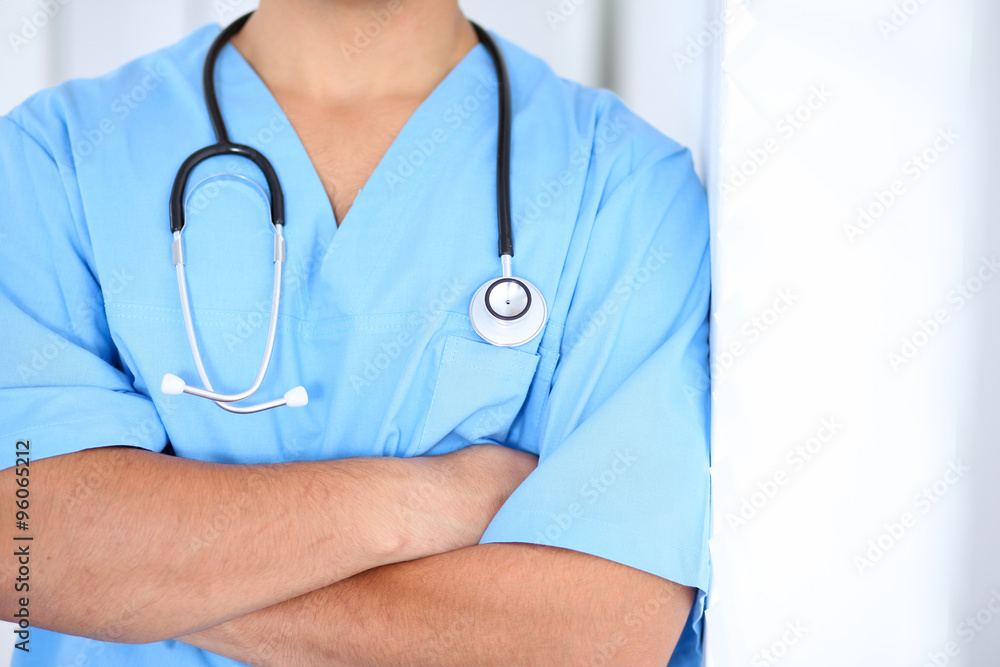 Portrait of unknown male surgeon doctor standing near the wall in hospital office Portrait of unknown male surgeon doctor standing near the wall in hospital office