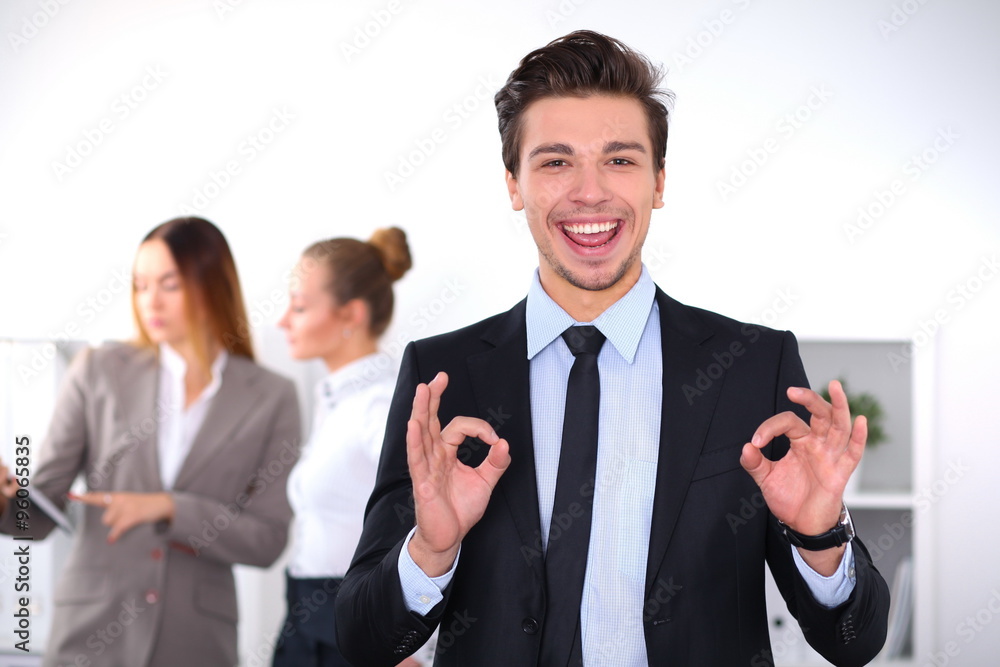 Cheerful business man in office with colleagues in the background, sturt up team Cheerful business man in office with colleagues in the background, sturt up team