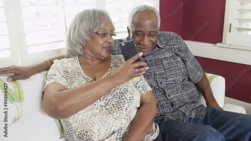 Happy senior African couple sitting on couch talking on phone Happy senior African couple sitting on couch talking on phone