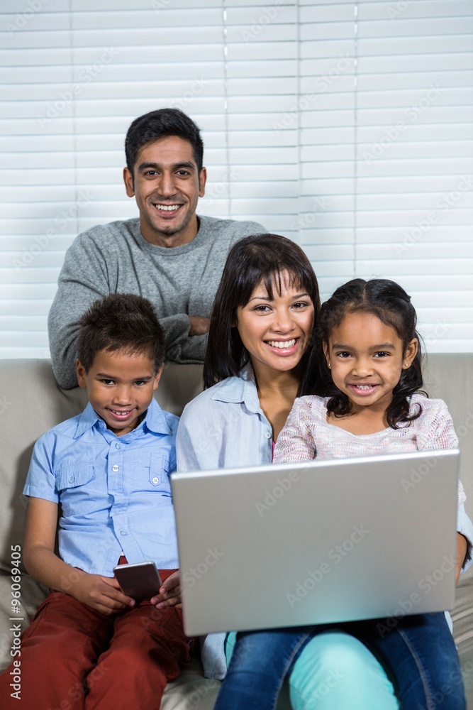 Smiling family using technology on the sofa