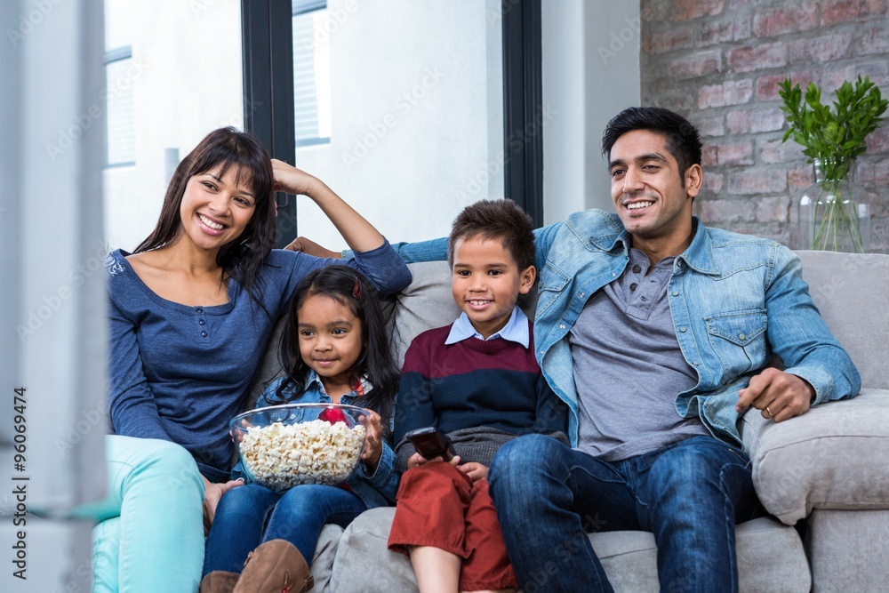 Happy young family eating popcorn while watching tv Happy young family eating popcorn while watching tv