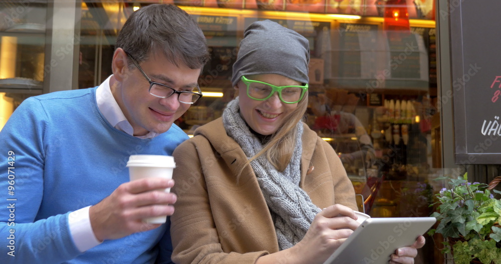 Happy Couple Using Digital Tablet At Street Cafe Happy Couple Using Digital Tablet At Street Cafe