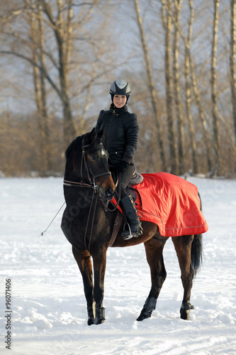 Romantic female jockey riding a horse winter outdoors 