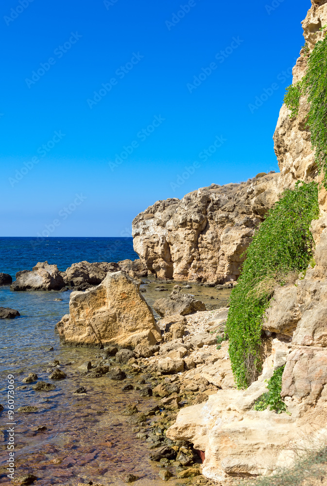 Mediterranean sea with green rocky beach.