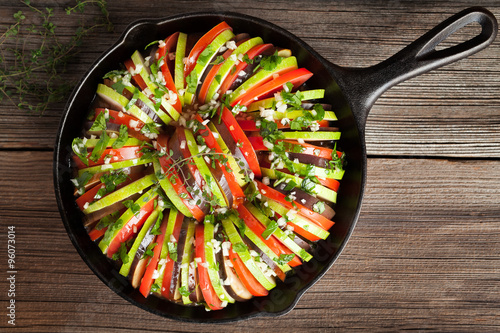 Traditional raw vegetable ratatouille in cast iron pan preparation recipe homemade healthy vegetarian food on vintage wooden table background
