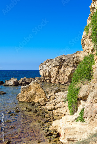 Mediterranean sea with green rocky beach.