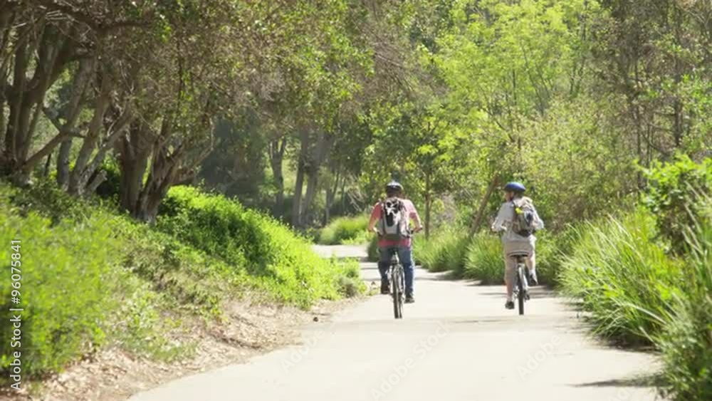 Active mature couple riding bikes outdoors on trail Active mature couple riding bikes outdoors on trail