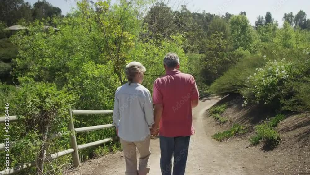 Senior married couple walking on trail together Senior married couple walking on trail together