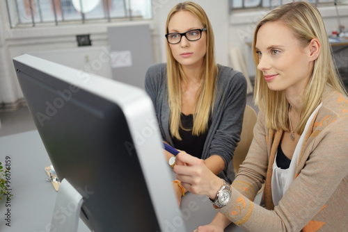 frau zeigt einer kollegin etwas am pc photo