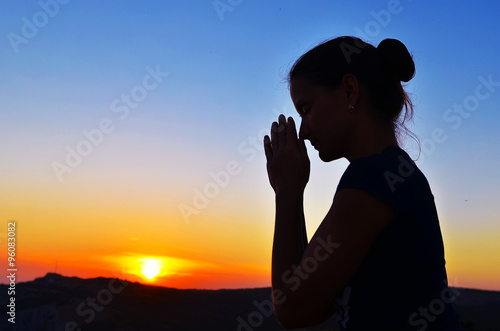 Girl folded her hands in prayer. Beautiful sunset. Colorful sky. Tenderness and serenity. beautiful summer Girl in prayer