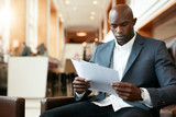 Young african businessman at hotel lobby reading documents