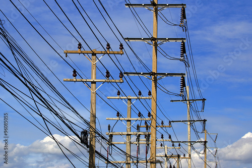  telephone utility poles , electric post ables, streetlights, and clear blue sky background. Neat rows of parallel distribution wires connected to three tall wood posts. Perspective view.