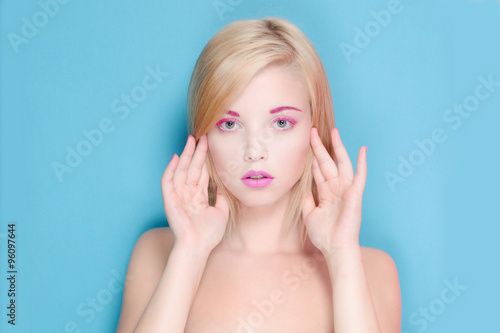 young woman blond hair on a blue background with pink makeup 