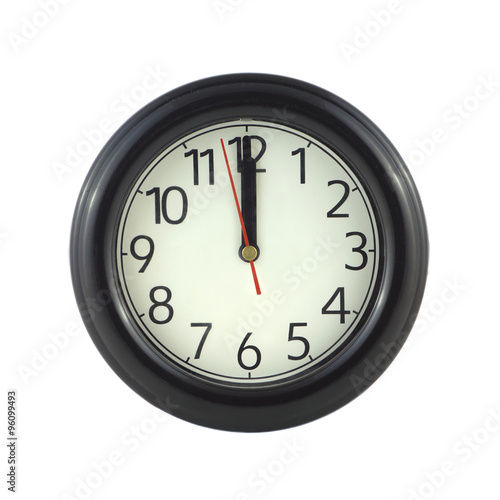 Big round wall clock in dark case shows almost twelve o'clock isolated on white closeup