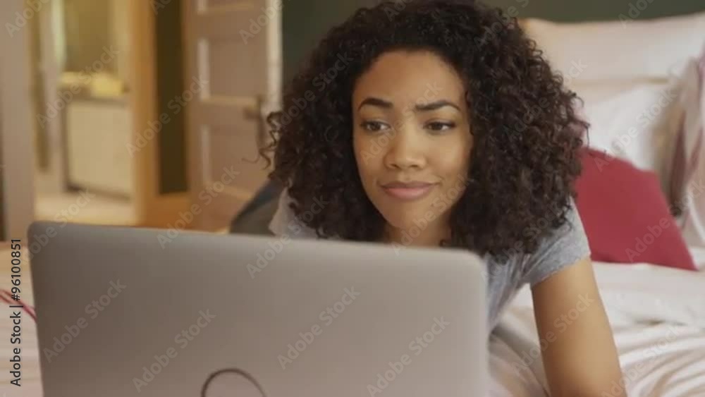 Black woman browsing the web on laptop at home