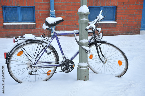 Snow covered bicycle on the street