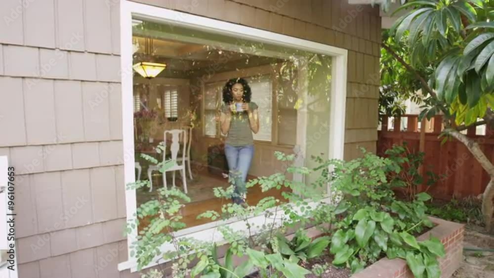 African woman with coffee looking through window African woman with coffee looking through window
