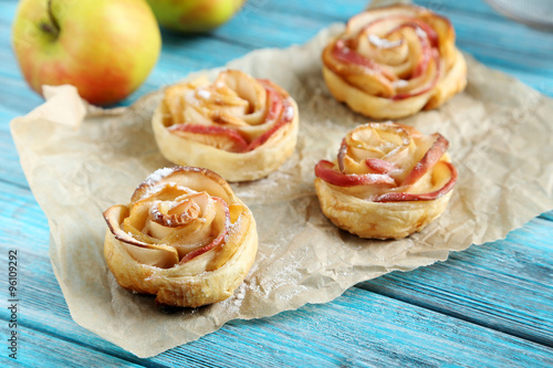 Fresh puff pastry with apple shaped roses on blue wooden table