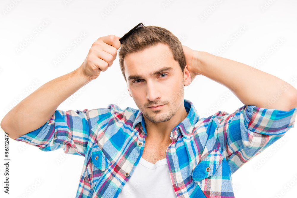 Handsome confident young man combing his hair Handsome confident young man combing his hair