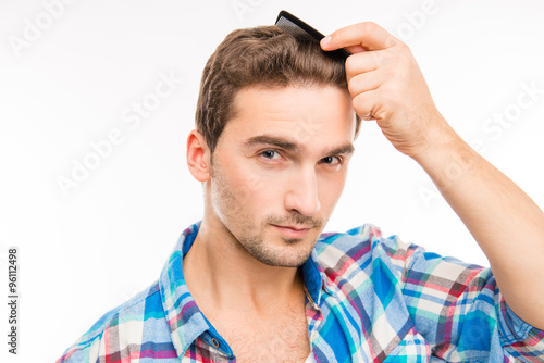 Handsome young man combing his hair