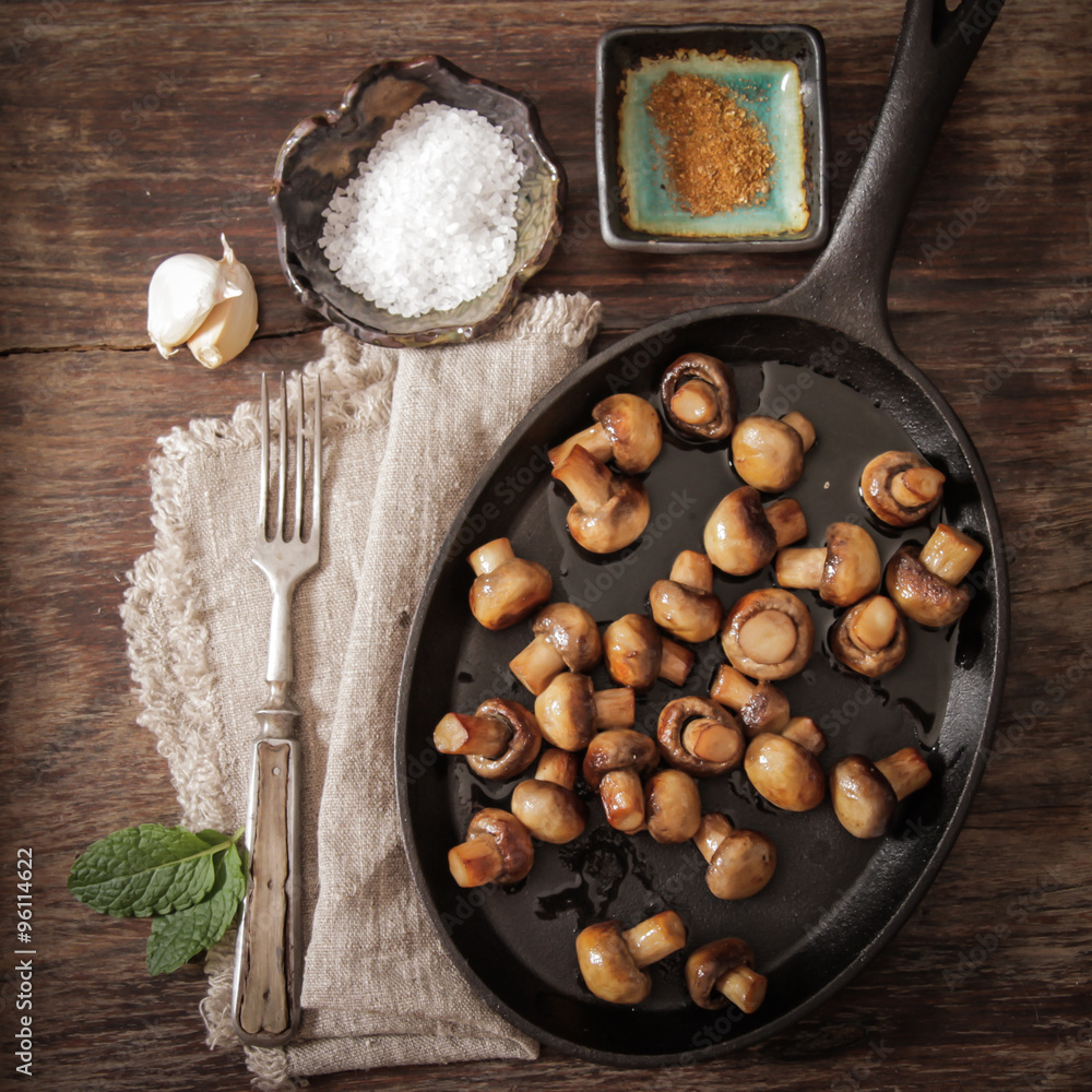 fried mushrooms with salt and pepper on a wooden background