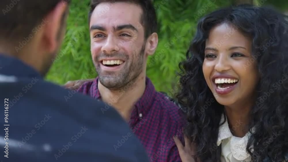 Over the shoulder shot of multi ethnic group of friends laughing smiling and talking Over the shoulder shot of multi ethnic group of friends laughing smiling and talking