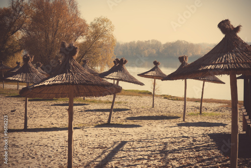 Empty river beach with parasols at autumn
