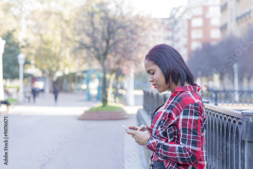 Smiling young woman with smart phone in the street. © leonardo2011