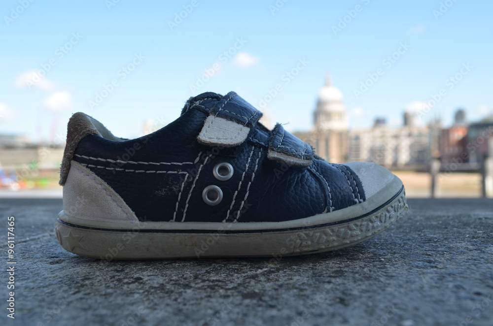 Naklejka premium Little abandoned children shoe on stone river dike, London