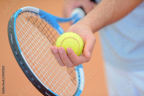 Closeup of hands holding tennis racket and ball, poised to serve © auremar