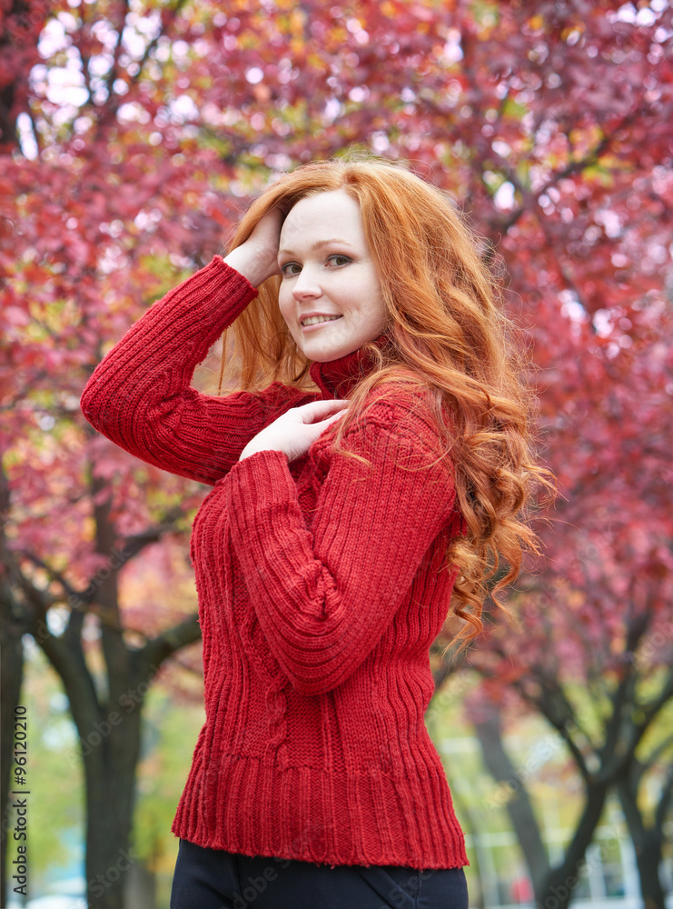 redhead girl in city park on red tree background, fall season redhead girl in city park on red tree background, fall season
