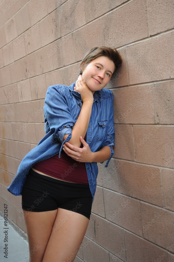 Female beauty fashion model posing against a wall outside. Female beauty fashion model posing against a wall outside.