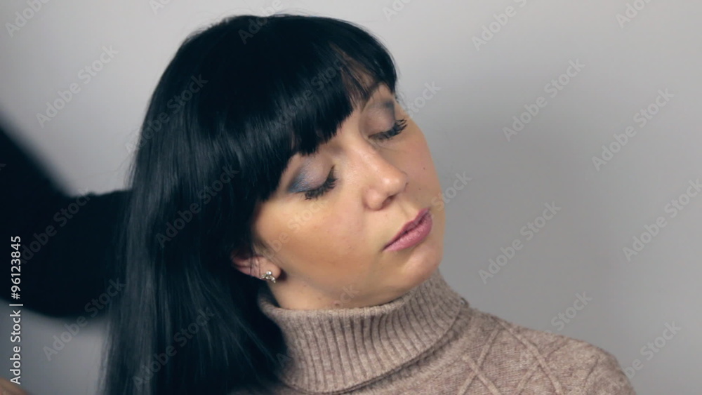 Hairdresser combing long hair beautiful brunette. Close up of professional female hairdresser combing long black female hair at salon Hairdresser combing long hair beautiful brunette. Close up of professional female hairdresser combing long black female hair at salon