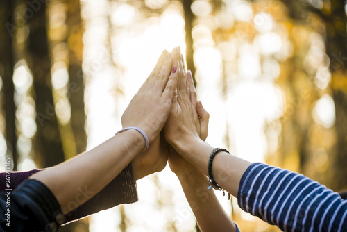 Closeup view of four people joining their hands together high up photo