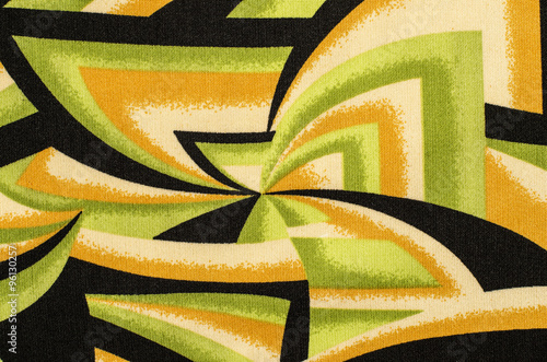 Abstract shapes pattern on fabric. Green with black and yellow geometric spyral shapes material as background. photo