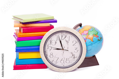 Many books with bright covers, globe and a wall clock on a white background
