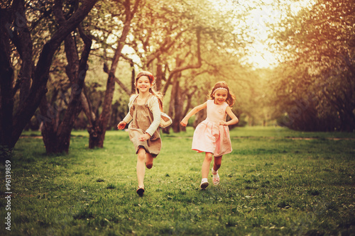 two happy dressy girls running on spring walk, outdoor activities, friendship concept