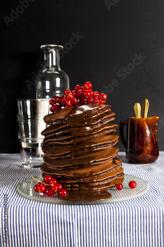 stack of pancakes on the tablecloth chocolate and fresh currants