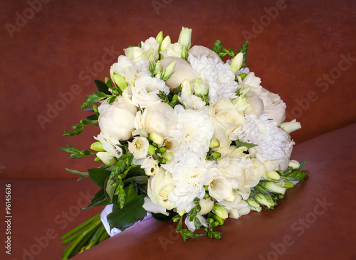 Bright flower wedding bouquet on the brown leather sofa.