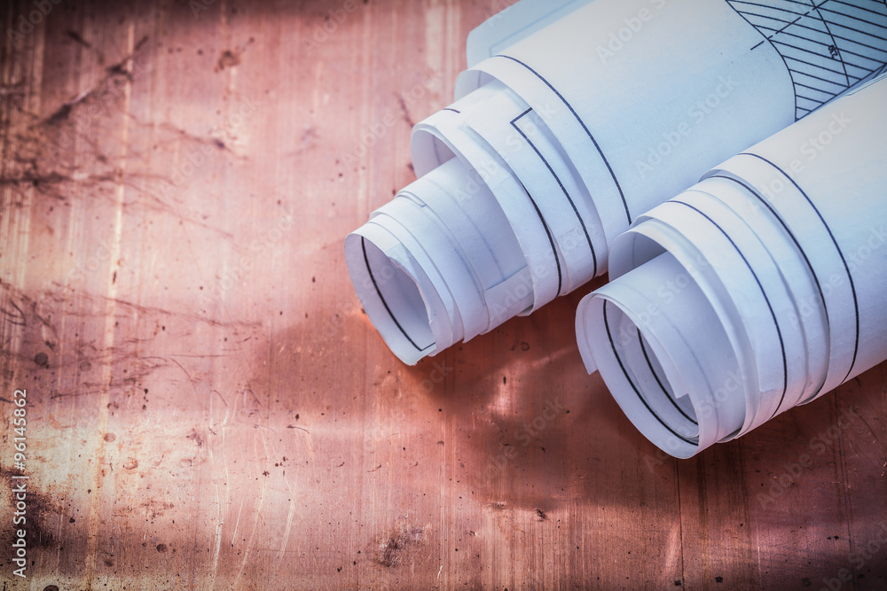 Rolled blueprints on brazen background construction concept