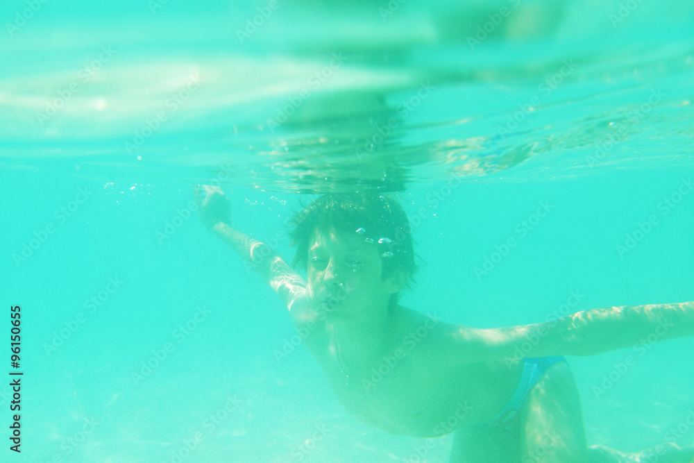 child swimming underwater in sea