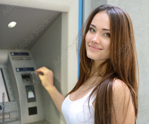 Young happy smiling woman using cash machine