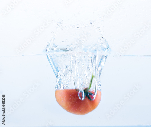 Frische halbe Tomate fällt ins Wasser