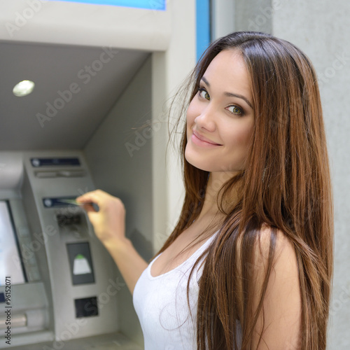 Young happy smiling woman using cash machine