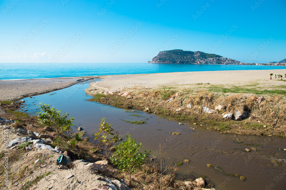 Confluence of the mountain river in the sea on beach in Alanya T