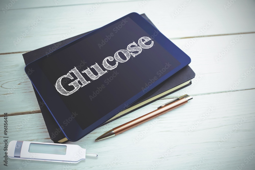 Obraz premium Glucose against view of a book and tablet lying on desk