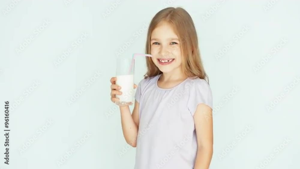 Happy child drinking milk. Girl with beautiful blond hair on a white background. Thumb up. Ok Happy child drinking milk. Girl with beautiful blond hair on a white background. Thumb up. Ok