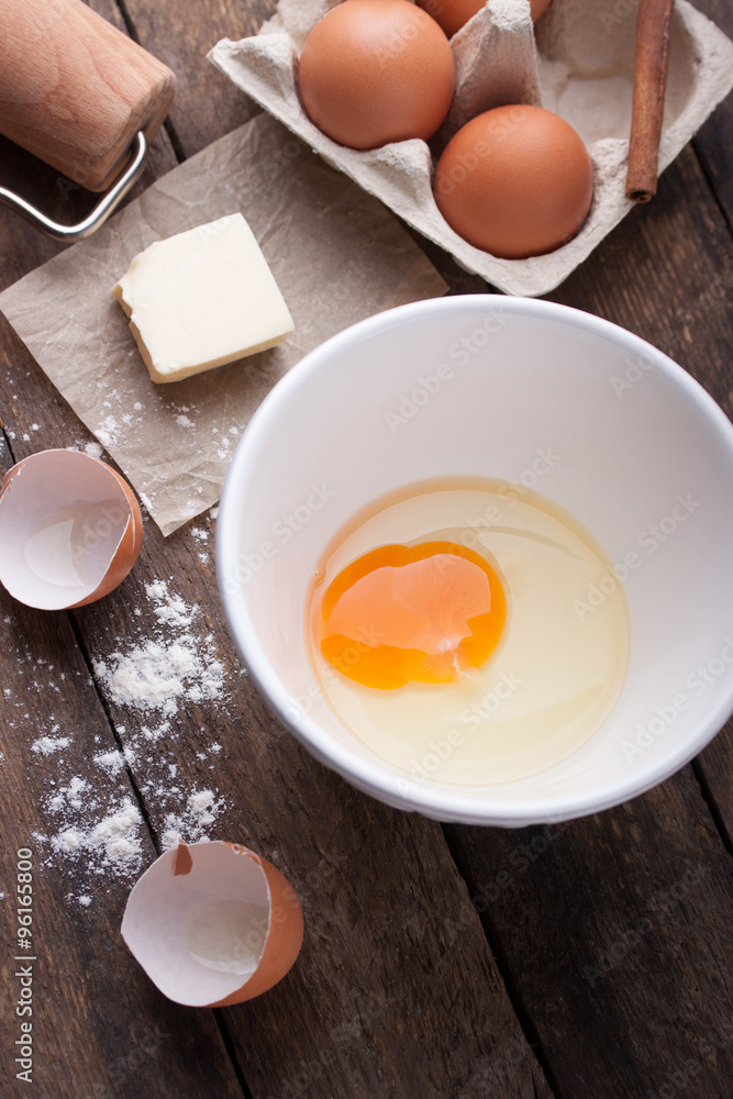 Ingredients and tools ready to make a cake, flour, eggs, butter, cinnamon stick on a wooden table Ingredients and tools ready to make a cake, flour, eggs, butter, cinnamon stick on a wooden table