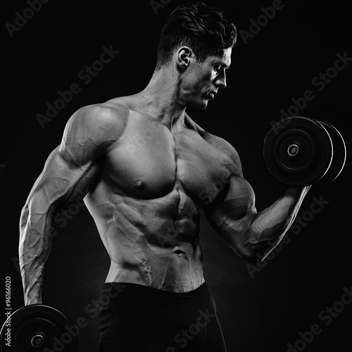 Handsome power athletic man in training pumping up muscles with
