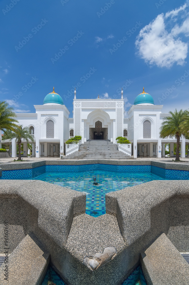 The vertical of Mosque Albukhary located in Alor Star, state of Kedah, Malaysia with its fountain and squares in the foreground and blue sky with clouds in the background.
